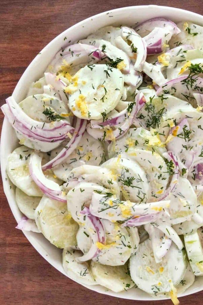 Creamy cucumber salad in a white bowl.