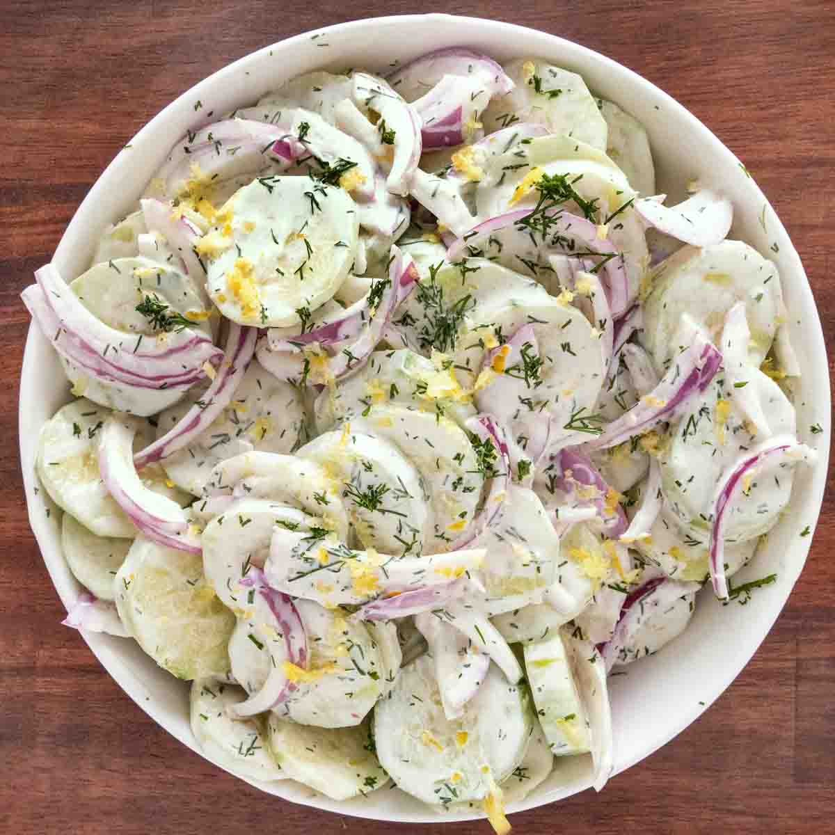 Creamy cucumber salad in a white bowl.