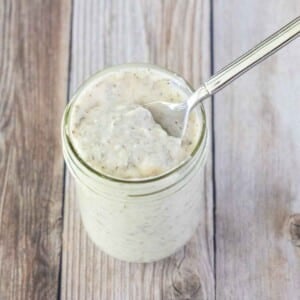 Creamy Italian dressing in a glass jar with a spoon in it.