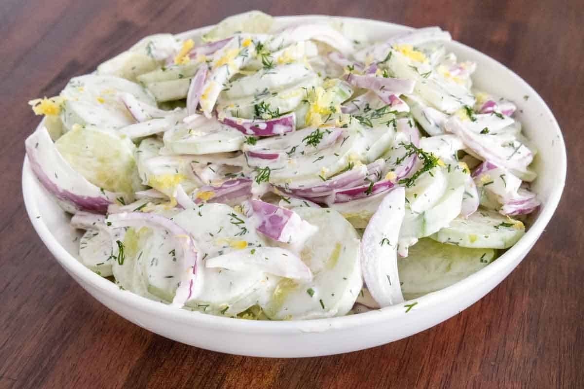 Creamy cucumber salad in a white bowl.