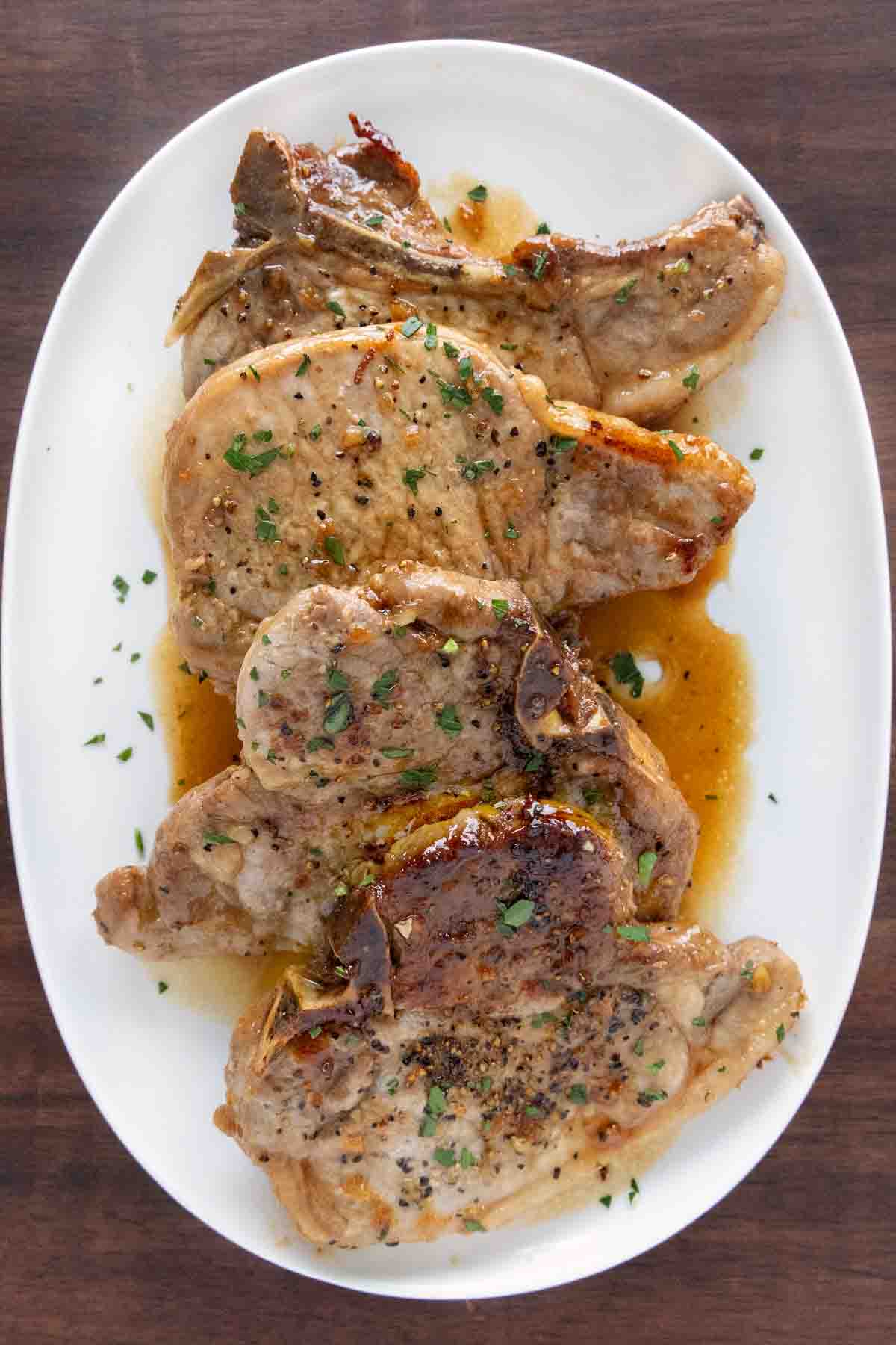Honey garlic pork chops on a white platter.