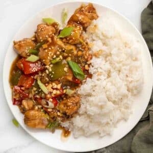 Kung pao chicken with rice on a white plate.