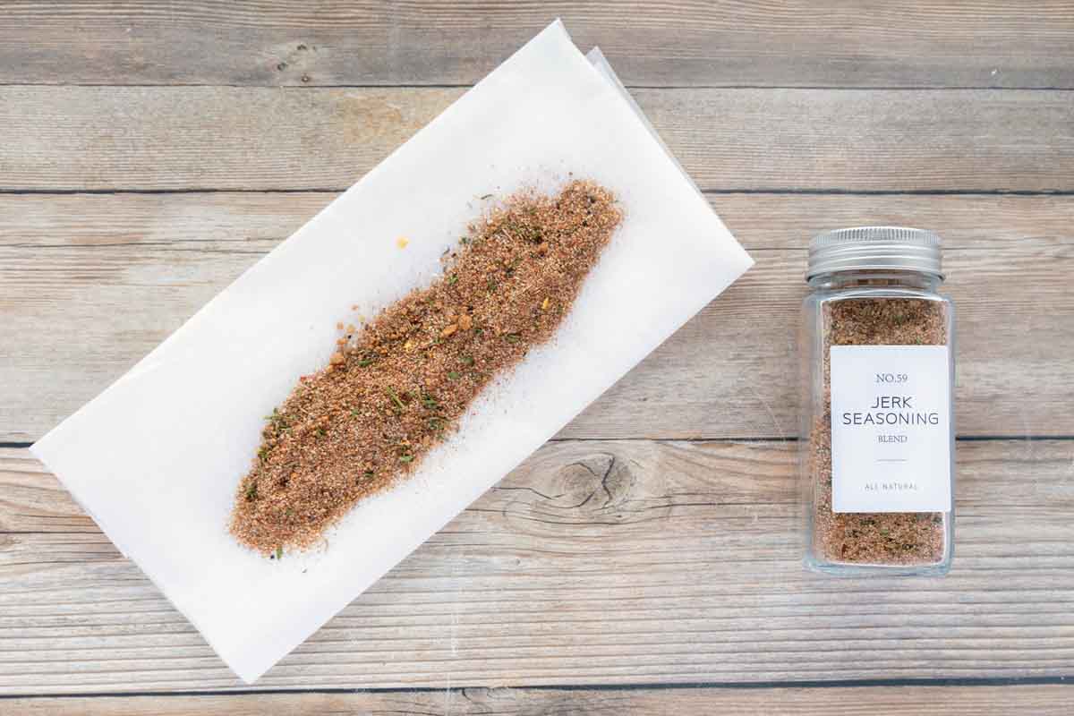Jamaican jerk seasoning in a bottle and spread on white butcher paper.