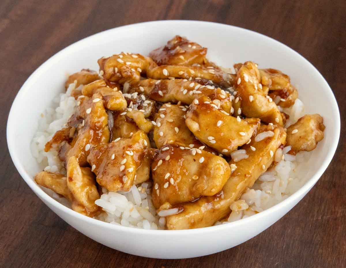 Bourbon chicken on a bed of rice on a white bowl.