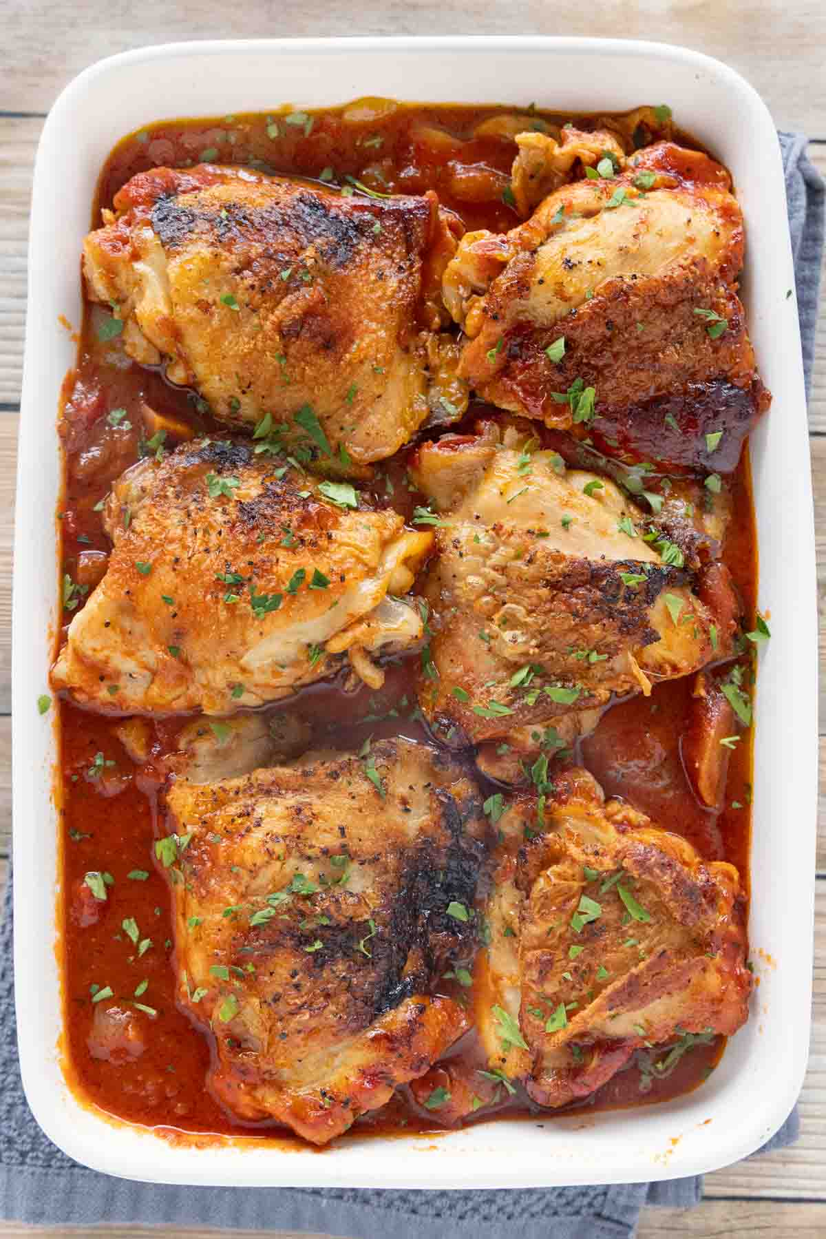 Braised Chicken thighs in a white casserole dish.