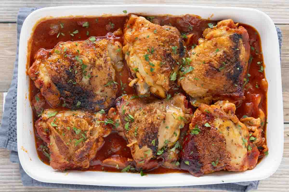 Braised Chicken thighs in a white casserole dish.