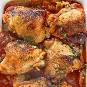Braised Chicken thighs in a white casserole dish.