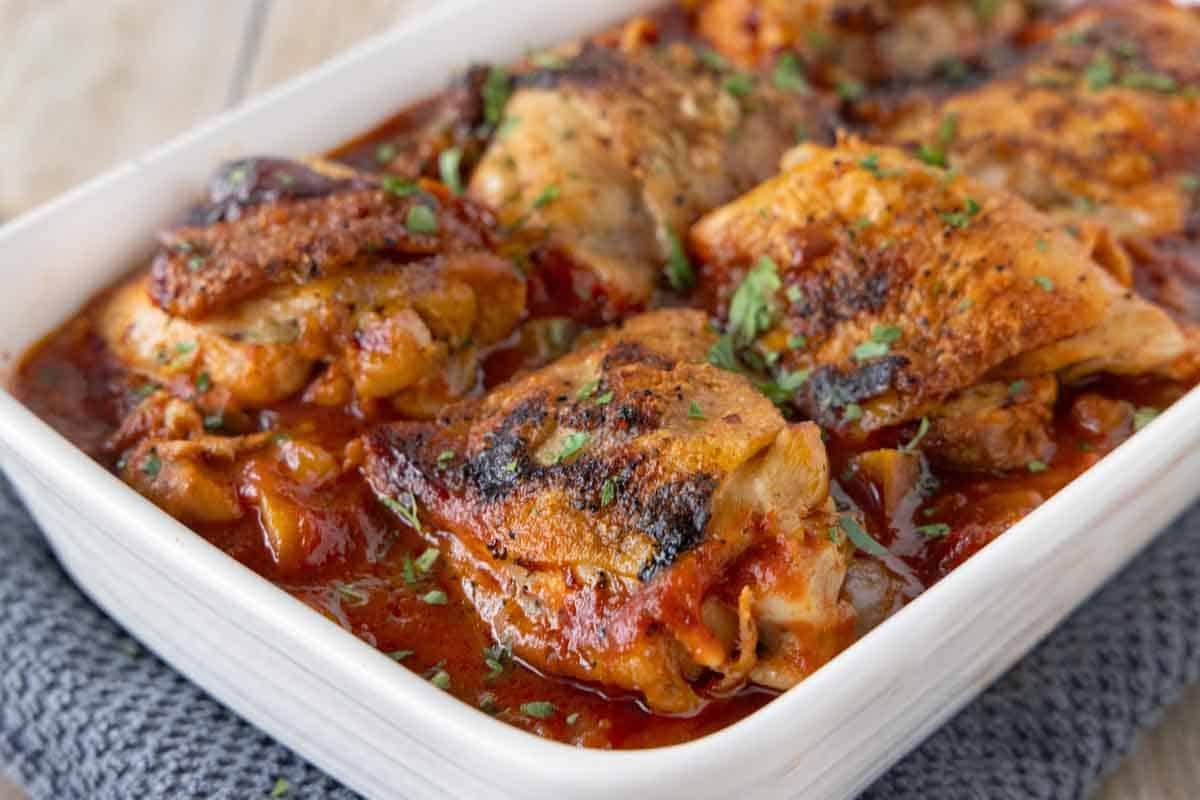 Braised Chicken thighs in a white casserole dish.