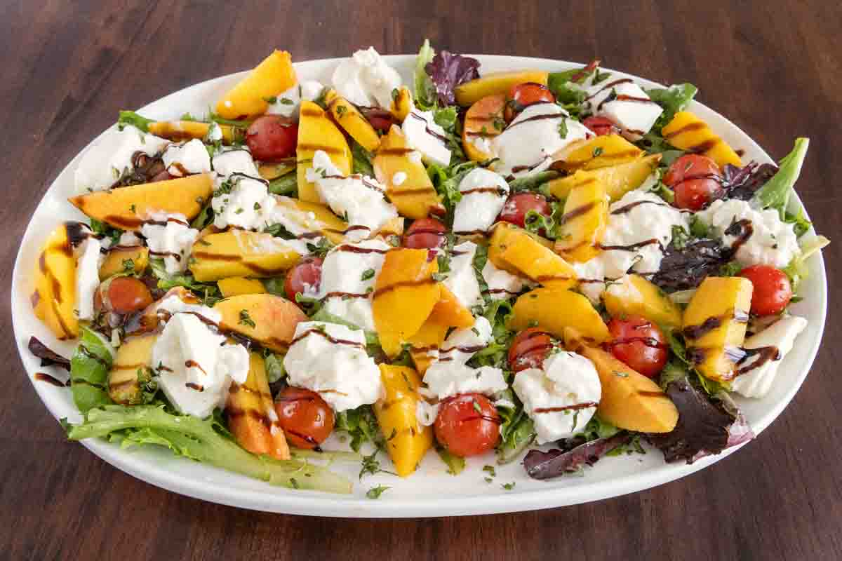 Burrata peach salad on a white platter.