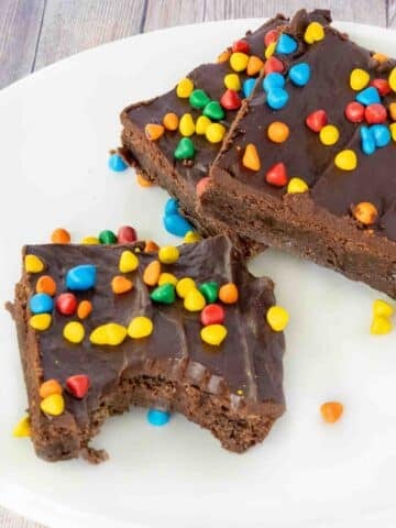 Cosmic brownies on a white plate, one with bite taken out.