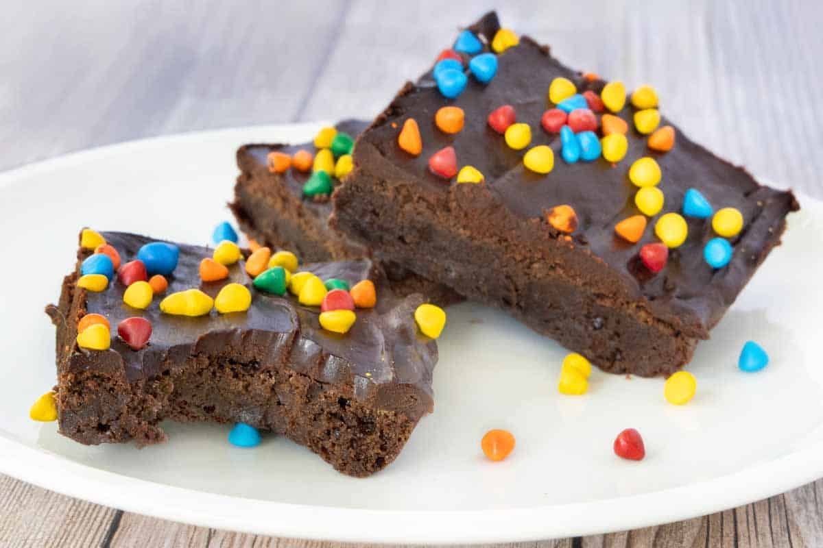 Cosmic brownies on a white plate, one with bite taken out.