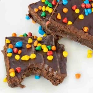 Cosmic brownies on a white plate, one with bite taken out.
