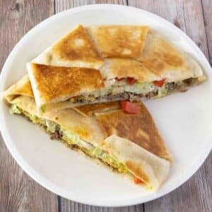 Crunch wrap supreme cut in half stacked on a white plate.