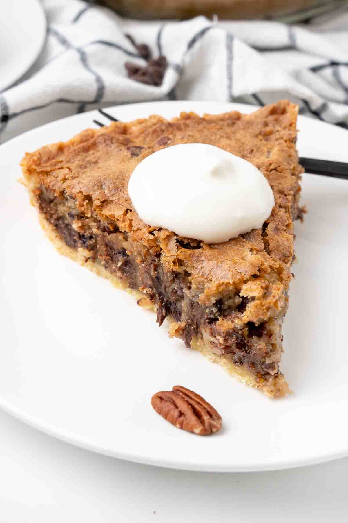 Slice of derby pie with whipped cream on a white plate.