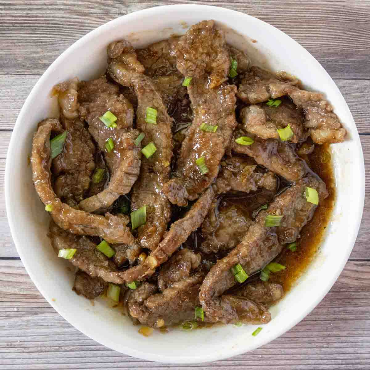 Mongolian beef in a white bowl.