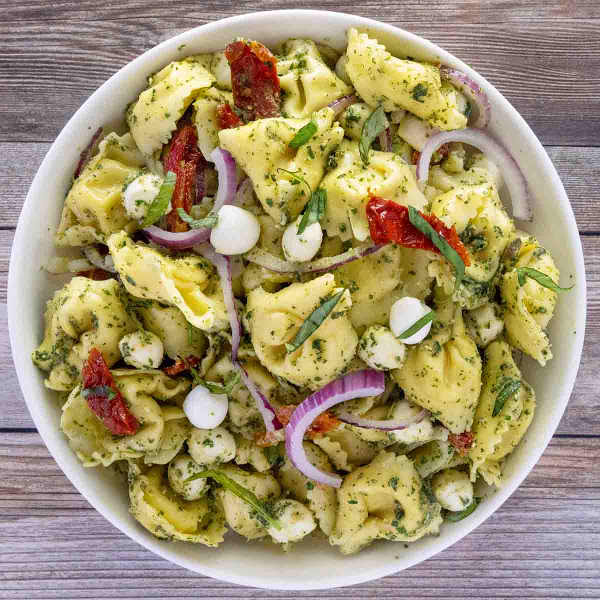 Pesto pasta salad in a white bowl.