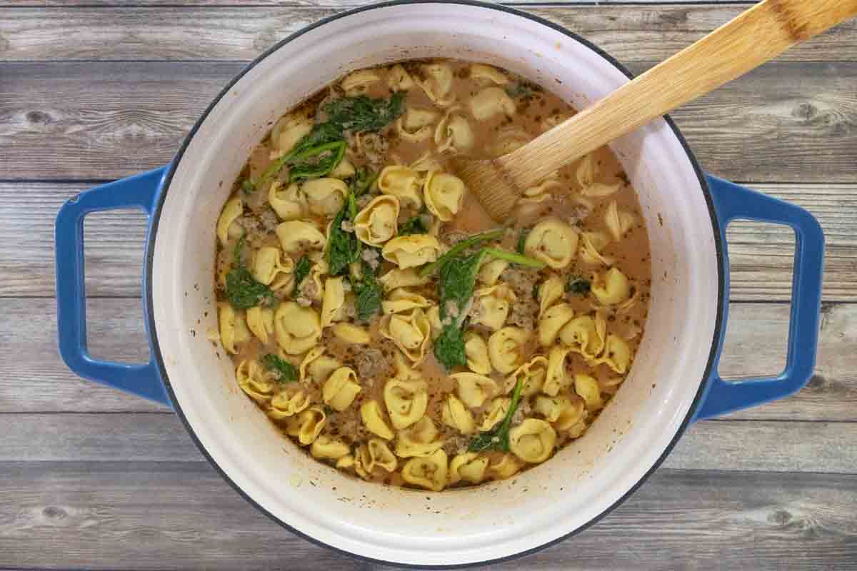 Finished soup in a Dutch oven with a wooden spoon.