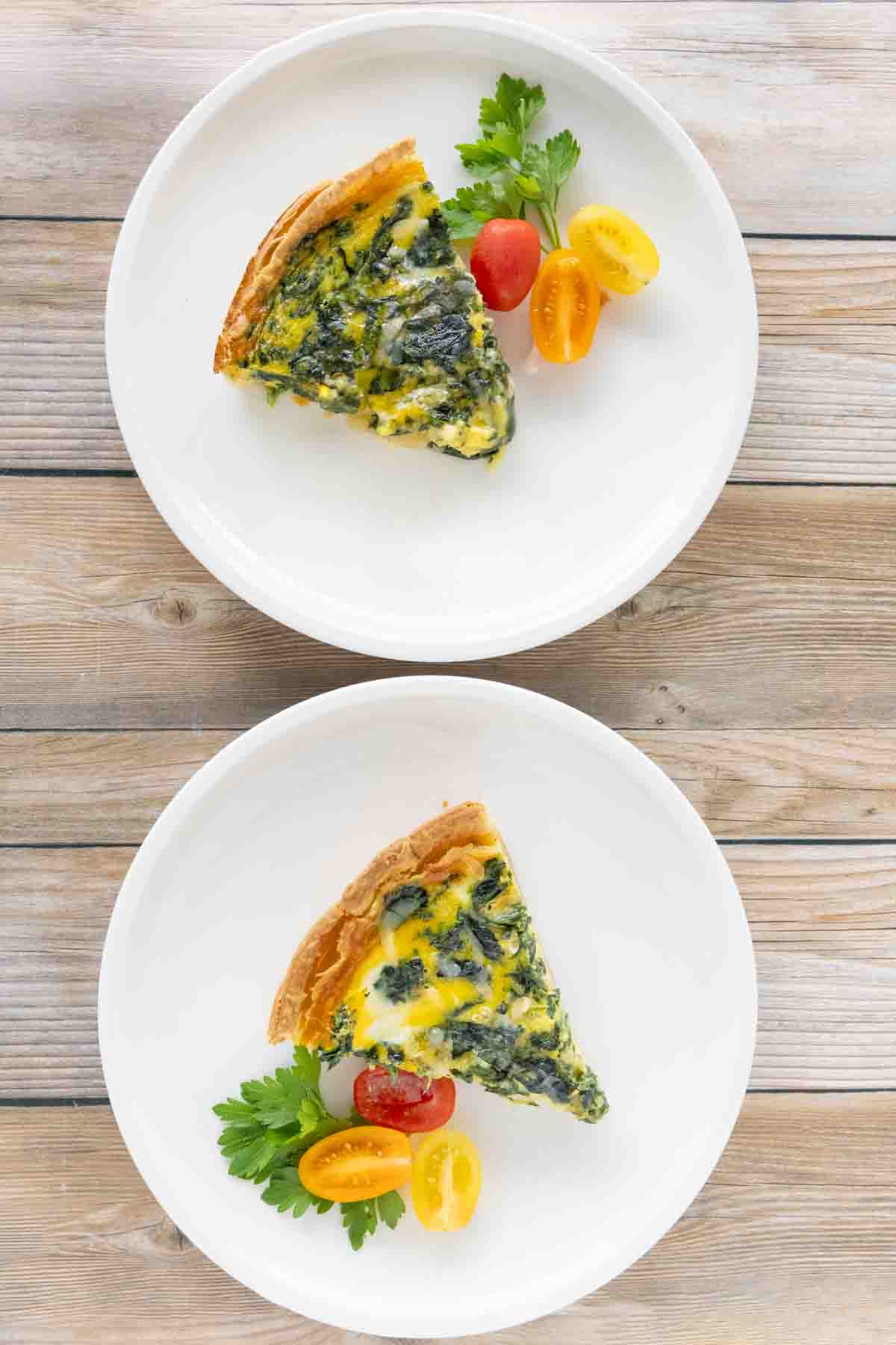 Two spinach quiche on white plates.