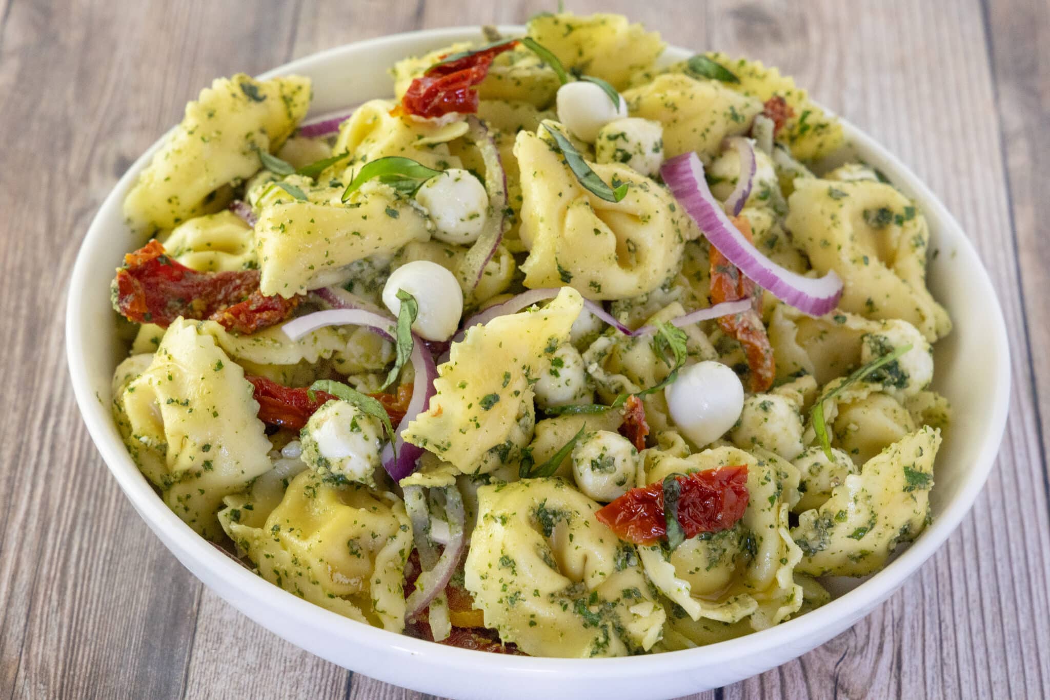 Pesto pasta salad in a white bowl.