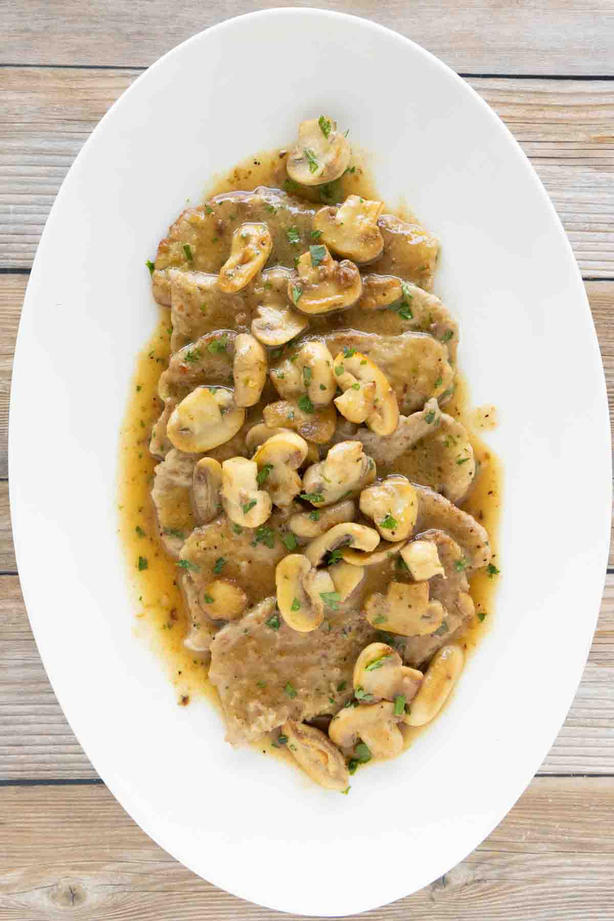 Veal scallopini on a white oval platter.