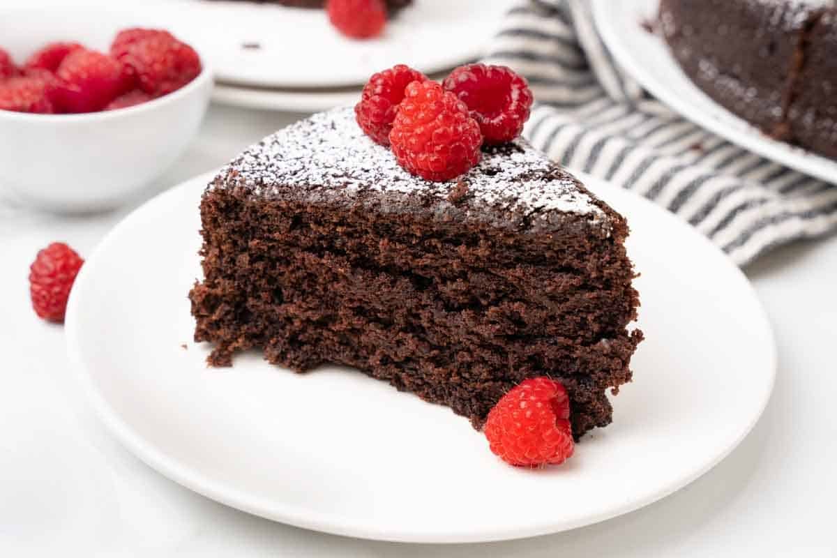 Cocoa cake on a white plate with raspberries.
