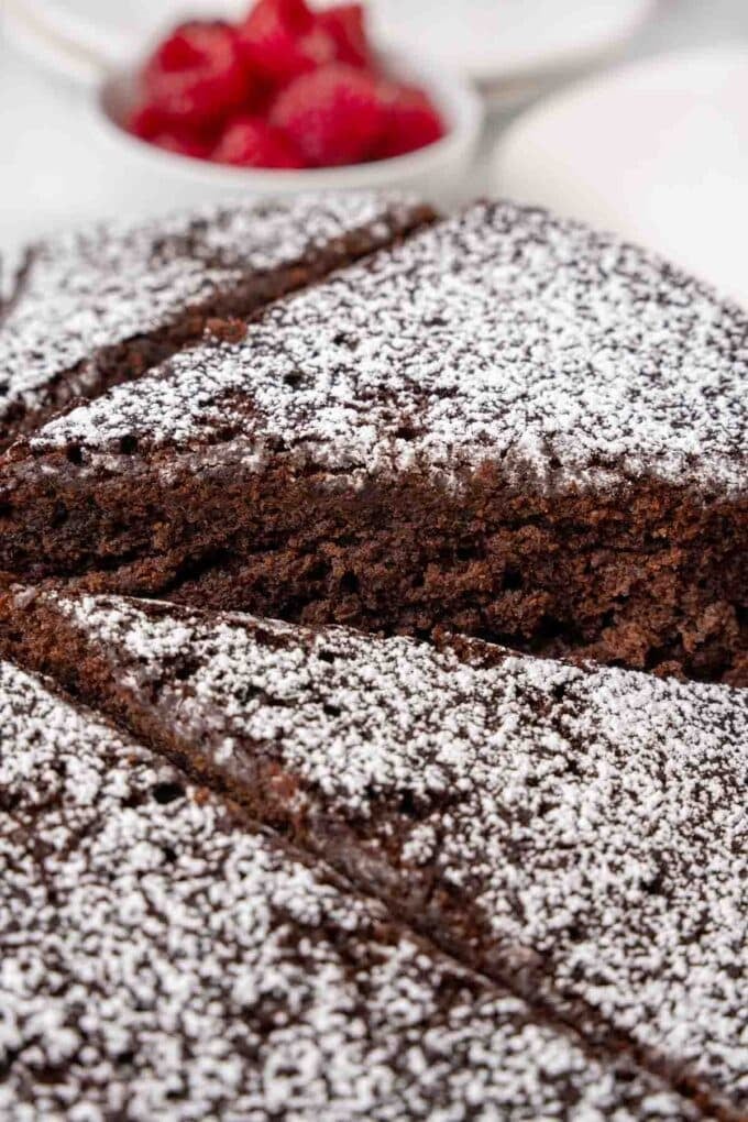 Slice of cocoa cake being take out of the whole cake.