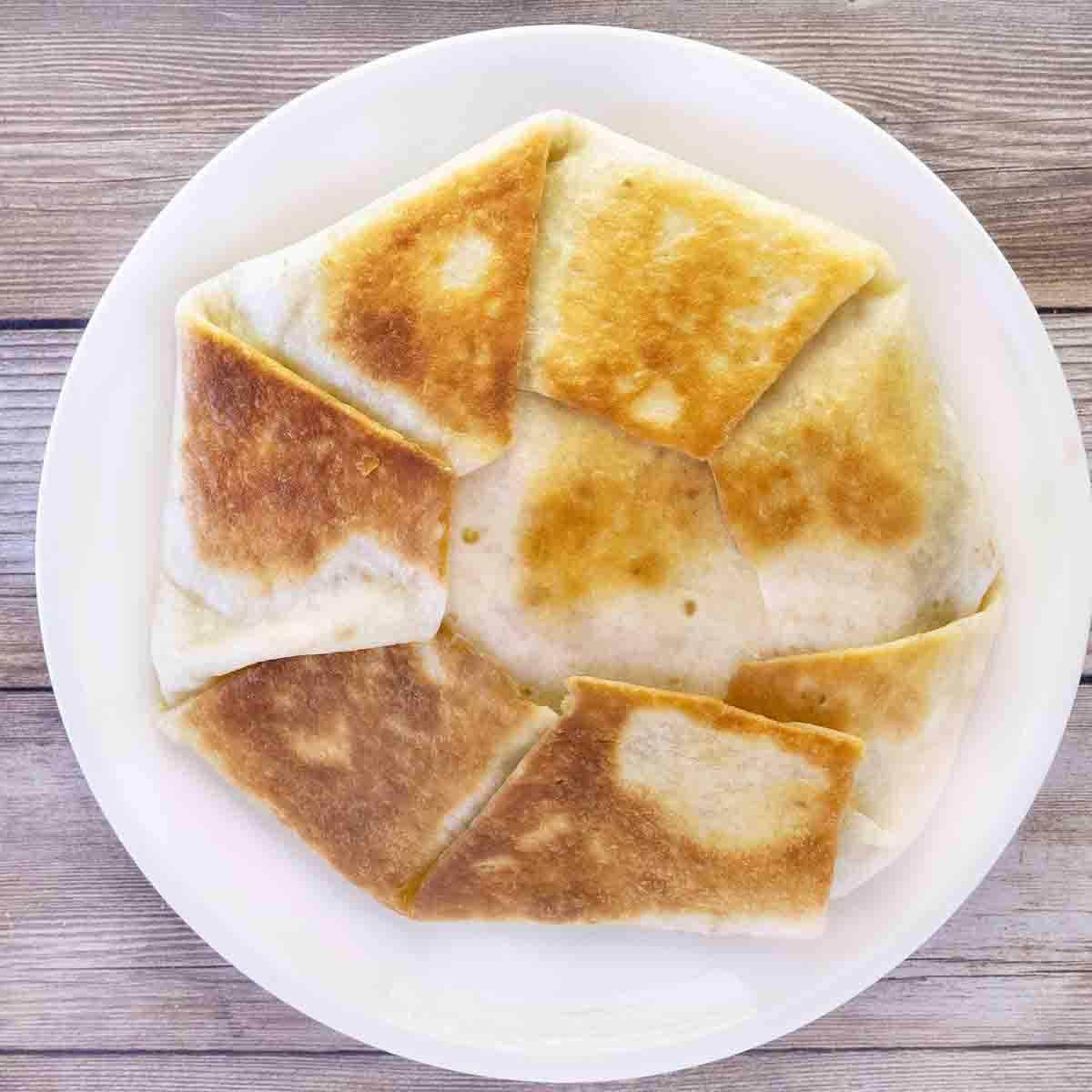 Finished whole crunchwrap supreme on a white plate.