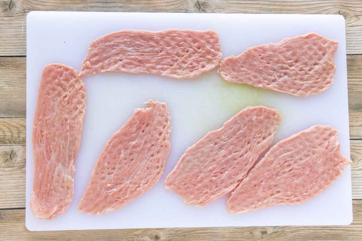 Veal pounded thin on a cutting board.