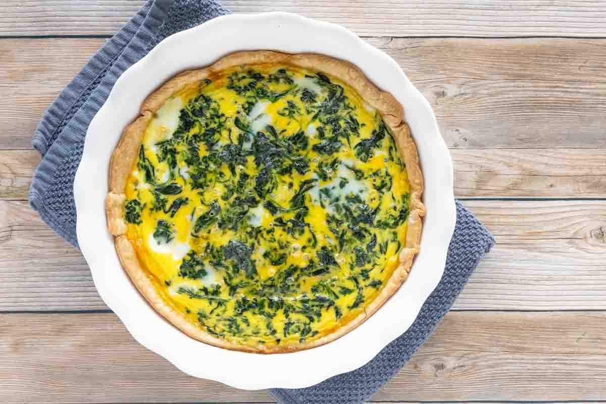 Whole spinach quiche in a white pie plate.