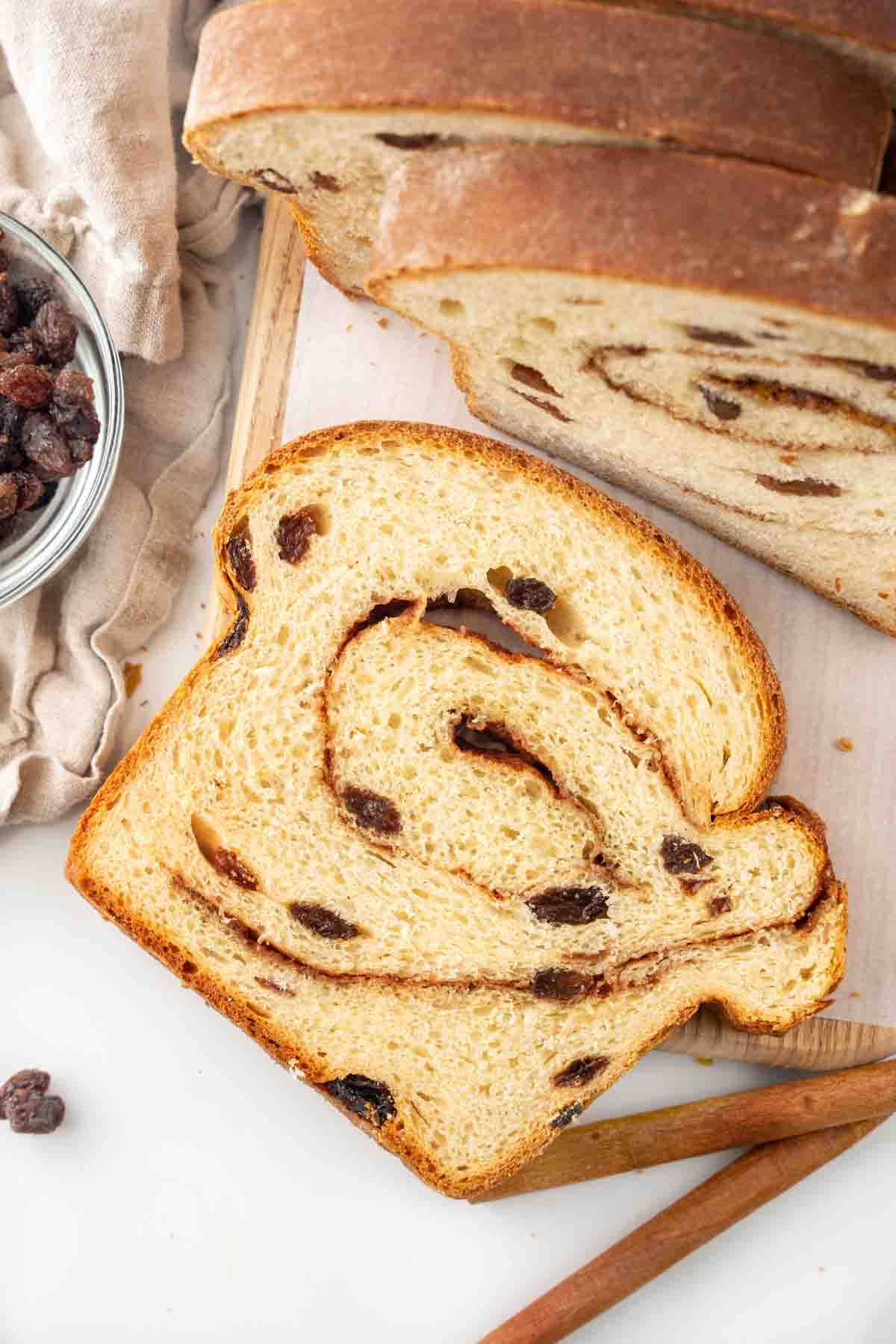 Slices of cinnamon raisin bread on a cutting board.