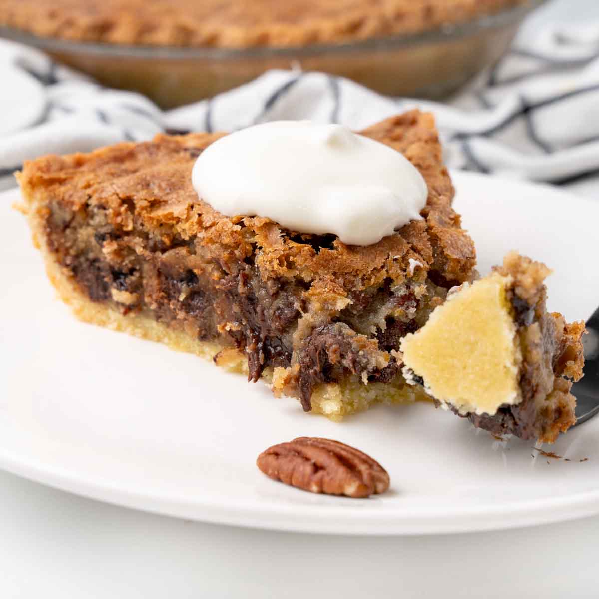 Slice of derby pie with a fork taking some out on a white plate.