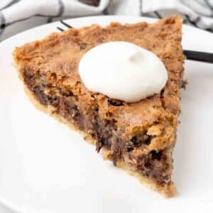 Slice of derby pie with whipped cream on a white plate.