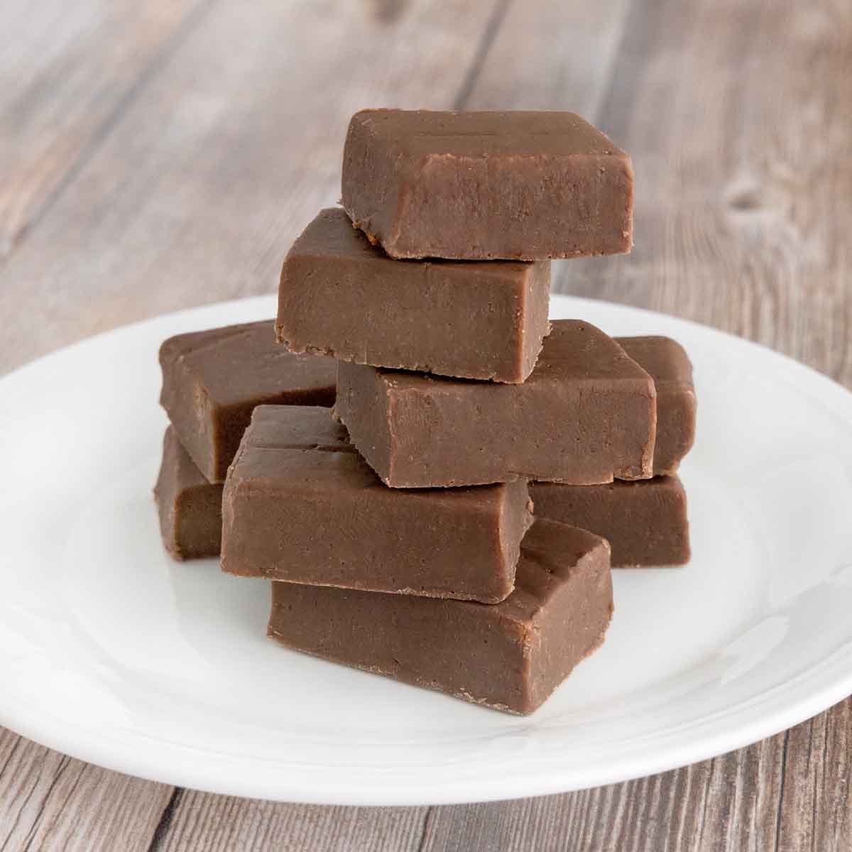 Chocolate fudge stacked on a white platter.
