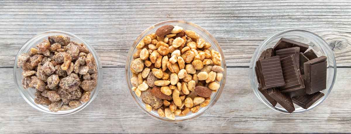 Nuts and chocolate in three small bowls.