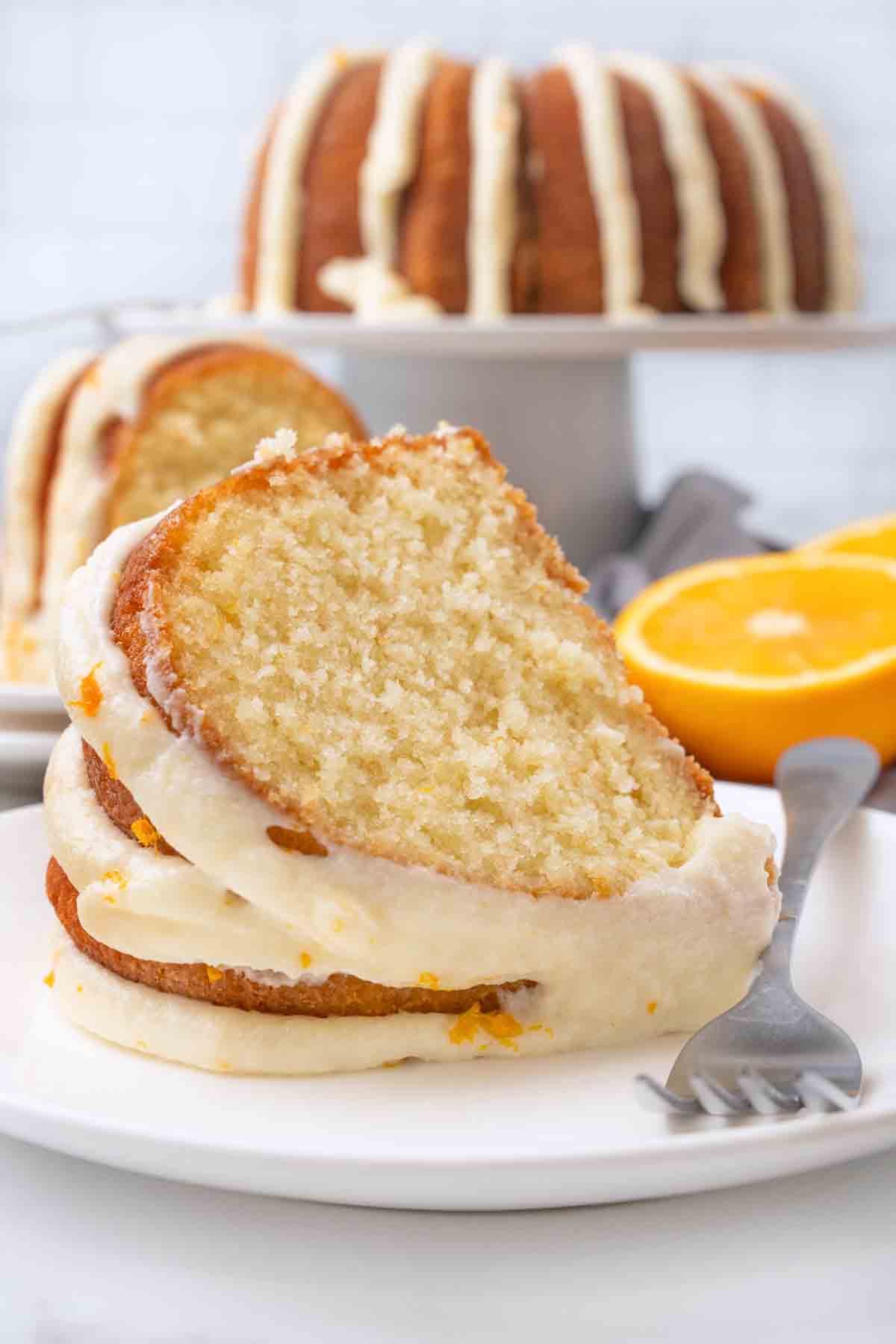 Slice of orange cake on a white plate with a fork.