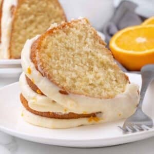 Slice of orange cake on a white plate with a fork