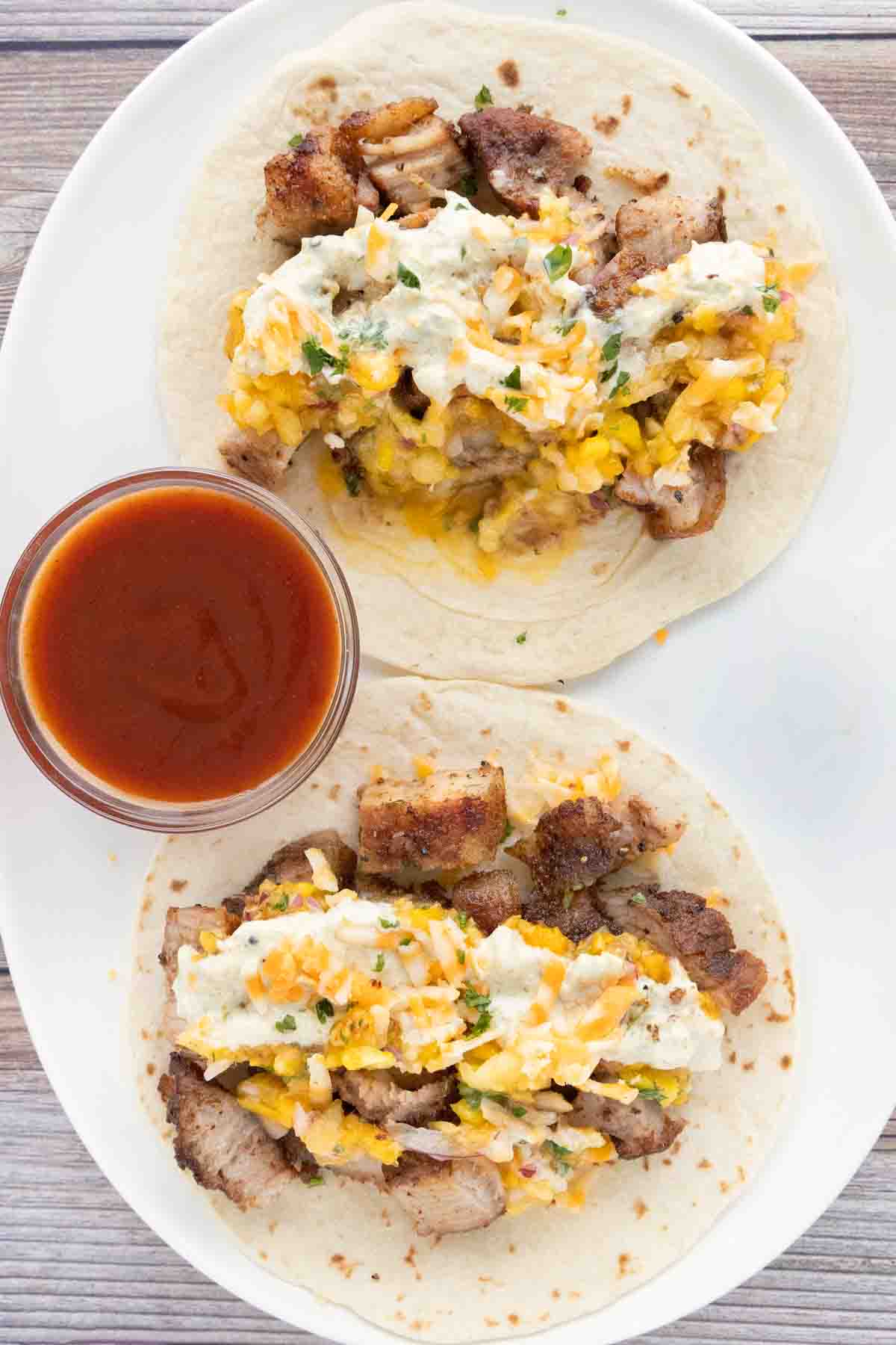 Pork belly tacos on a white platter.