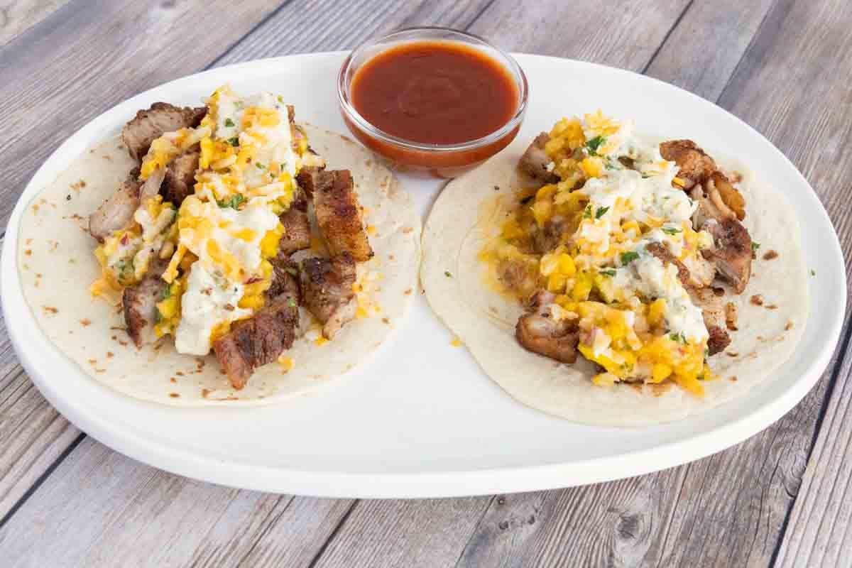 Pork belly tacos on a white platter.