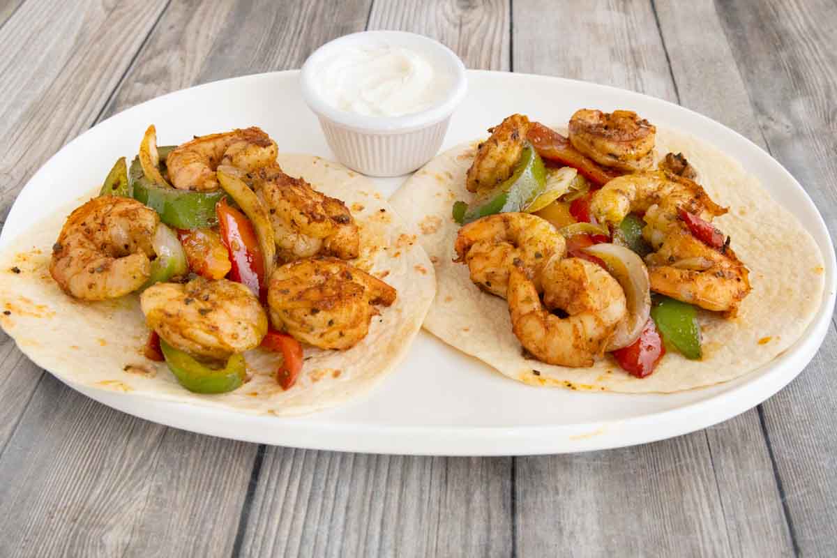shrimp fajitas on a white platter.