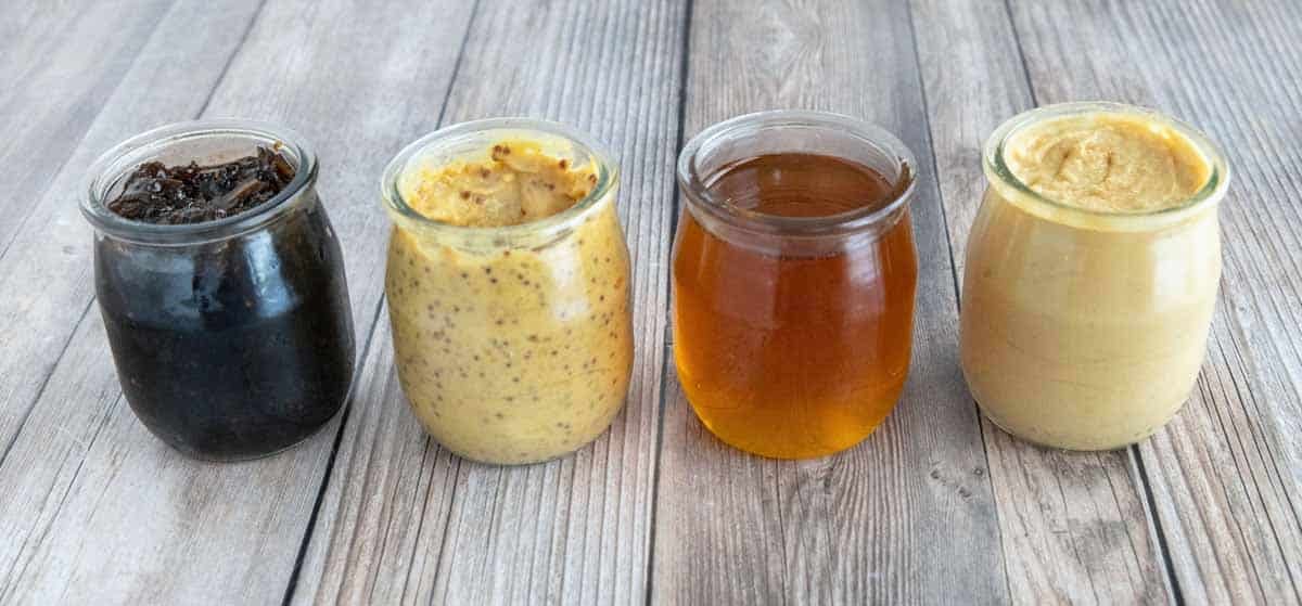 Mustards, honey and jams in 4 small jars.