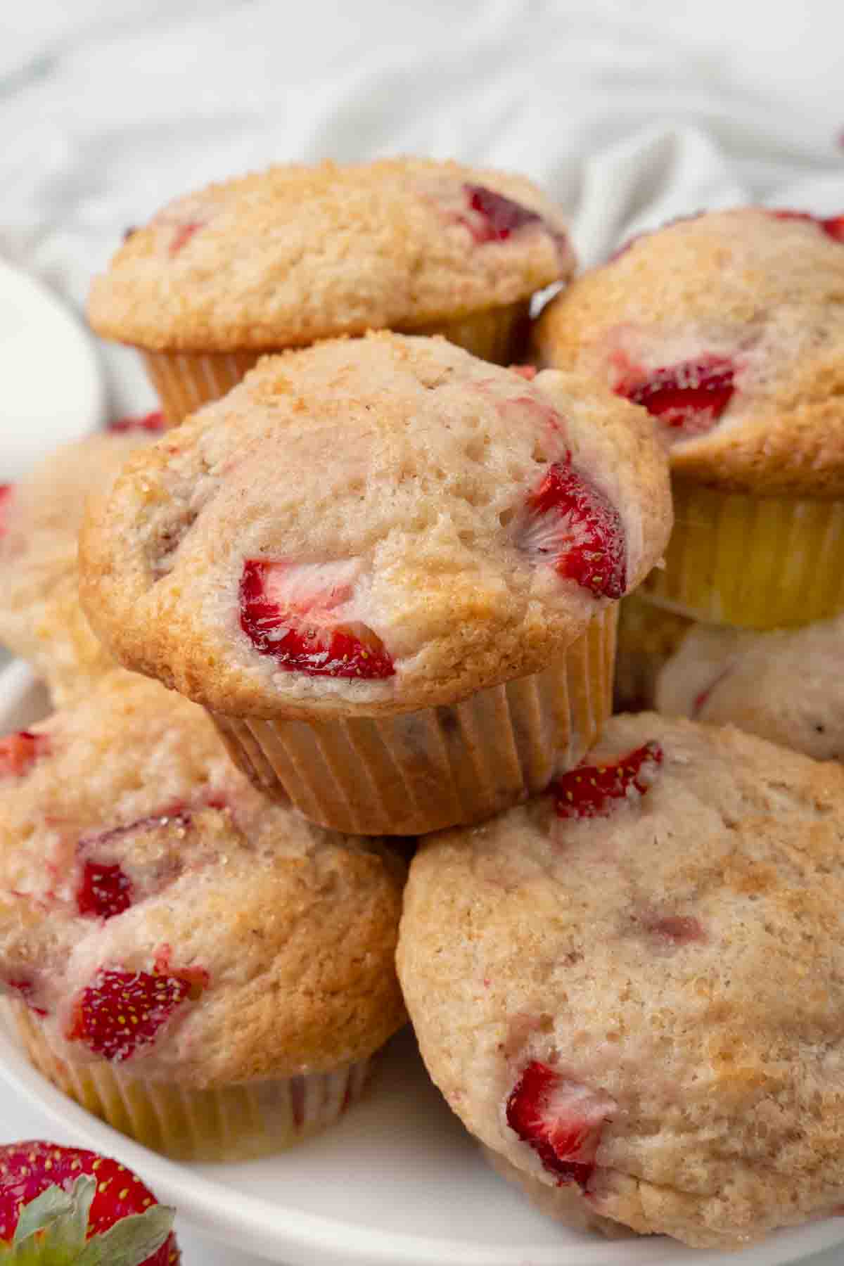 Strawberry muffins stacked on a white platter.
