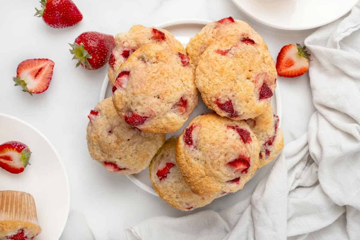 Strawberry muffins stacked on a white platter.