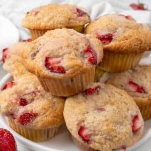 Strawberry muffins stacked on a white platter.