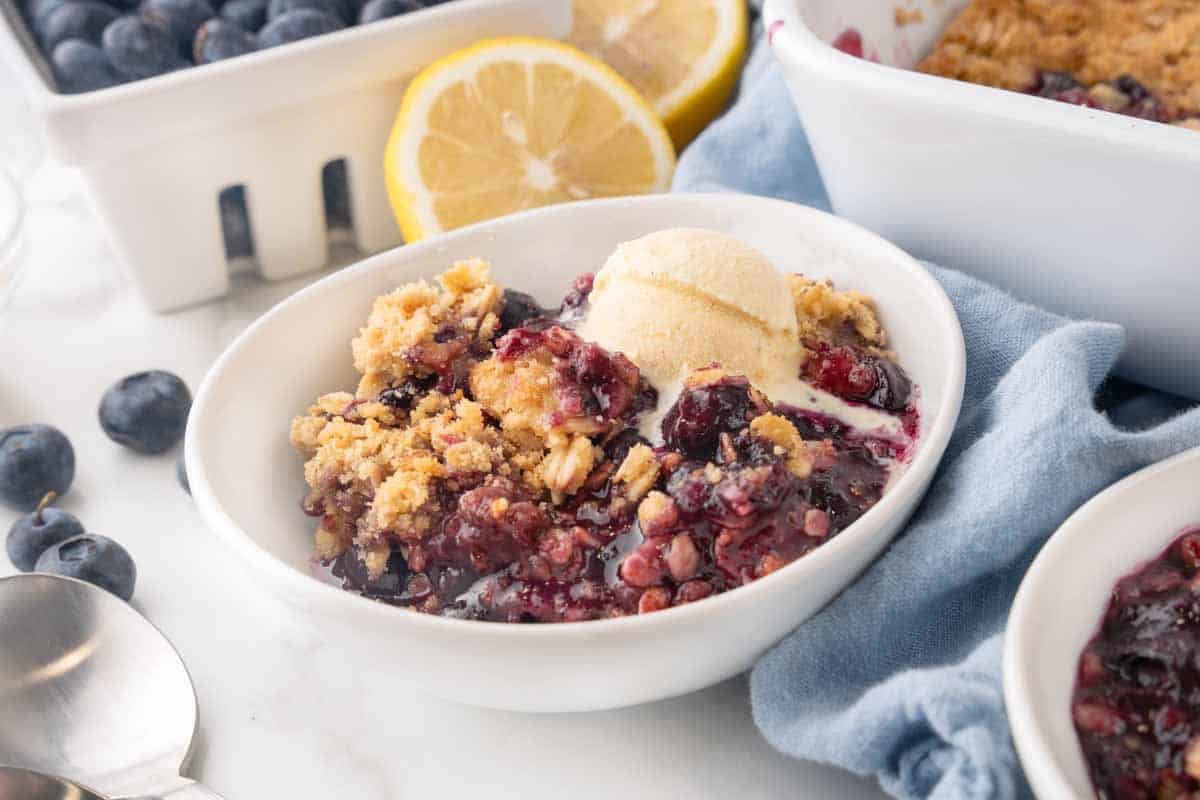 blueberry crumble with vanilla ice cream in a white bowl.