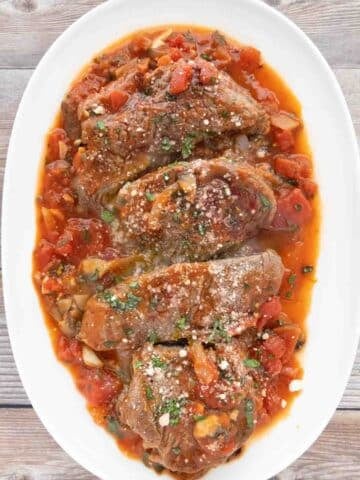 Steak Pizzaiola on a white platter.