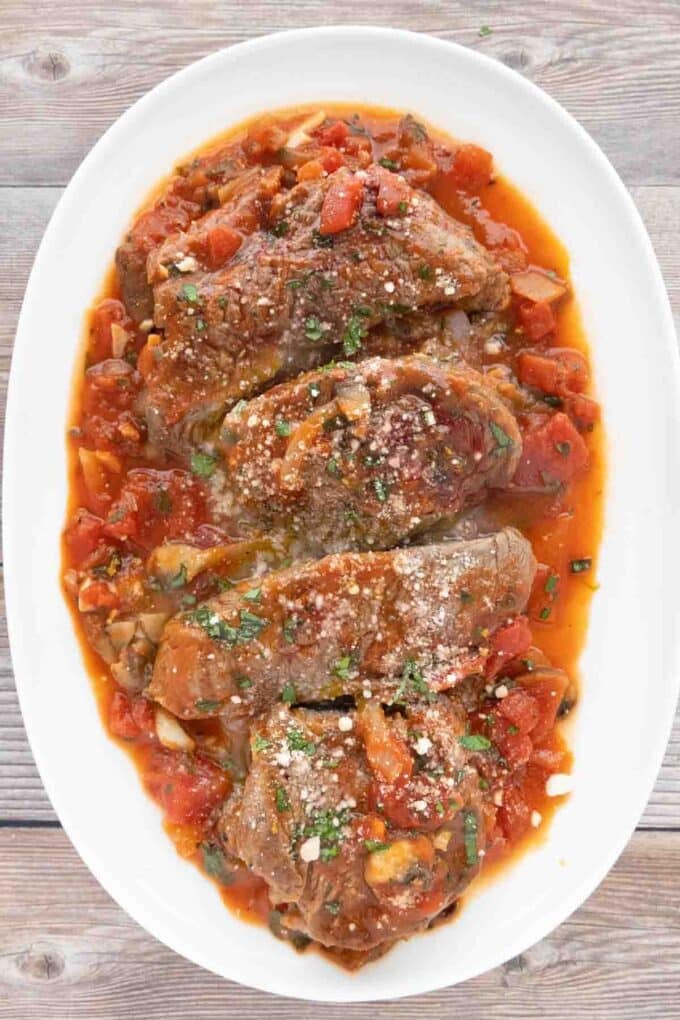 Steak Pizzaiola on a white platter.