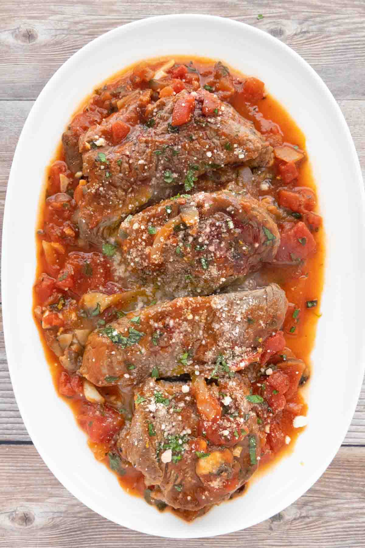 Steak Pizzaiola on a white platter.
