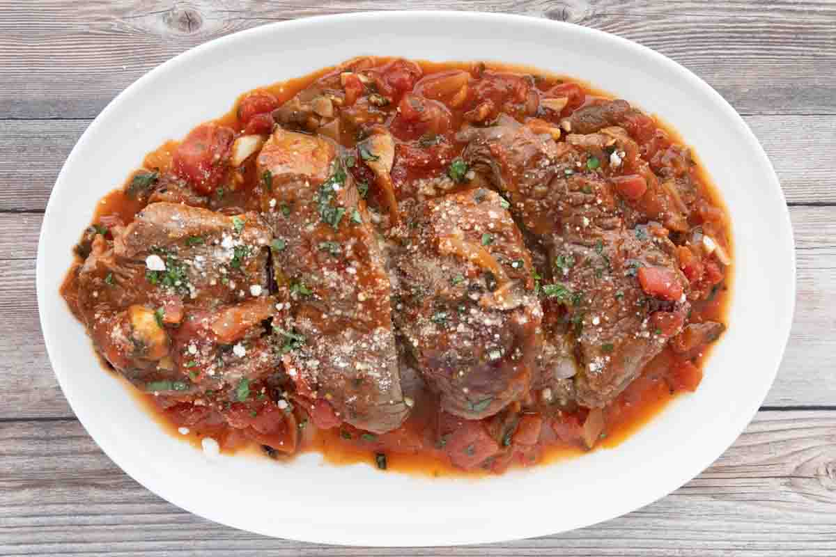 Steak Pizzaiola on a white platter.