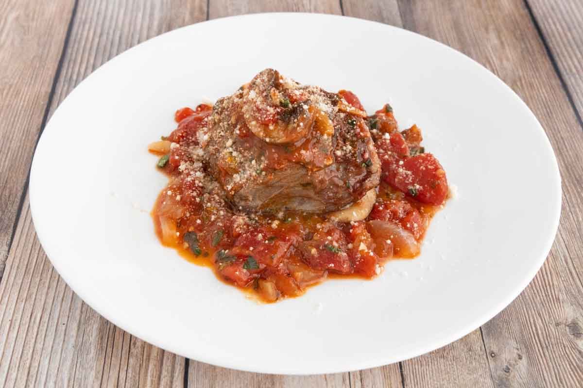 Steak Pizzaiola on a white plate.