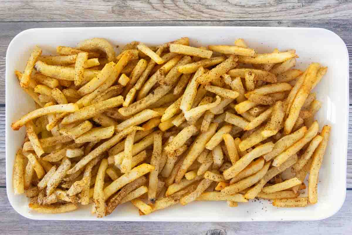 Seasoned French Fries on a white platter.